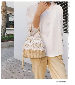Detailed view of the woven straw bucket bag with delicate white lace floral embroidery
