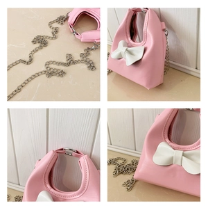 Detail of pink mini bag showing white bow, silver chain strap, and smooth PU leather