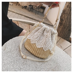 Close-up of straw bucket bag featuring white floral lace detail and gold-tone hardware