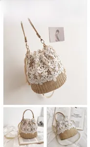 Detailed view of floral lace stitching on straw bucket bag with leather strap
