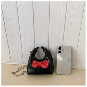 Size comparison of mini black bow crossbody bag with a phone for reference