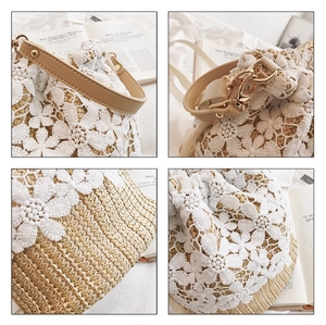Detail view of straw bucket bag featuring intricate white lace floral appliques and leather strap