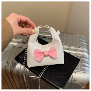Close-up of mini white girl's bag with a pink bow and silver chain strap