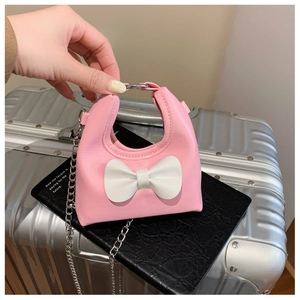 Detailed shot of a mini pink girl's bag featuring a large white bow and silver chain strap