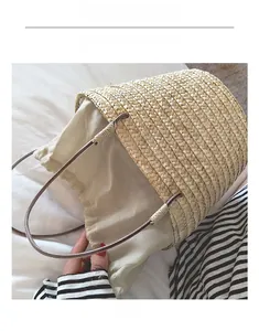 Detail of straw woven bucket bag featuring canvas drawstring lining and brown strap