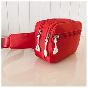 Detailansicht der roten Nylon-Gürteltasche mit mehreren Reißverschlussfächern und Griffen