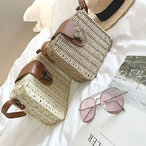 Detail of square straw beach bag with brown leather lid and vintage metal buckle closure