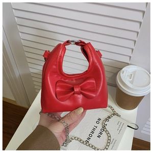 Detail of red bow children's mini bag with silver round handle and metal chain strap