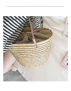 Detail shot of straw bucket bag with drawstring liner and slim leather strap on a model