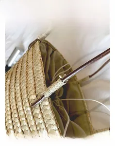 Detail of the woven straw bucket bag handle attachment with durable metal ring connectors