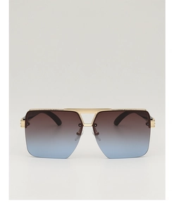 Macro detail of oversized pilot sunglasses featuring gold metal frame and gradient lenses