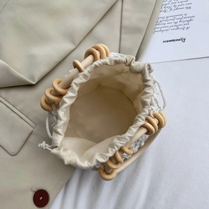 Woven cotton rope bucket bag with wooden ring handles and drawstring inner pouch