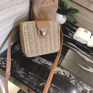 Detailed view of woven straw crossbody bag with brown leather clasp and bronze metal buckle