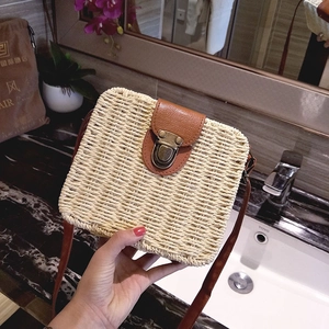 Detail of summer straw crossbody bag featuring beige weave and brown leather flap