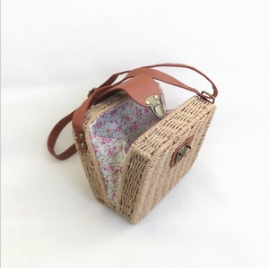 Handmade straw crossbody bag with brown leather strap and floral lining in a 45-degree view