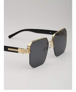 Detail of trendy polygonal sunglasses with gold striped metal temples and dark gray lenses