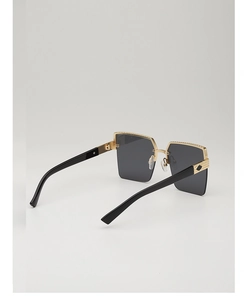 Detail view of gold metal hinges and black wide temples on retro square sunglasses