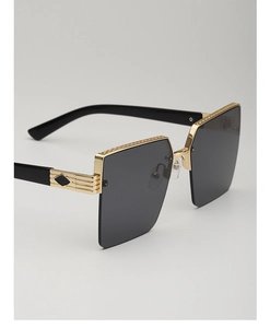 Detail of oversized gold metal half-frame sunglasses with engraved texture and black temples