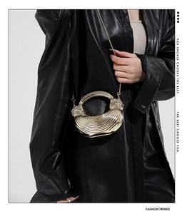 Detailed view of gold acrylic evening bag with metallic ridges and round handle