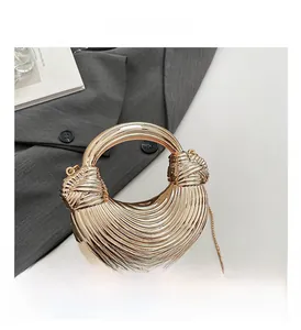 Detail of gold crescent evening bag with ring handle and metal chain on grey suit