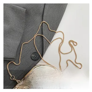 Detail of polished gold metal ring handle and dense snake chain strap for evening bag
