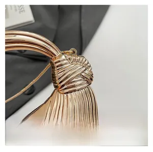 Detail of gold mirror acrylic mini bag with radial stripes and 3D knot design with chain