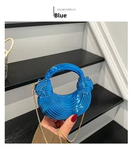 Detail of blue electroplated acrylic mini bag with ring handle and gold chain strap