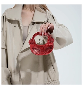 Detail of red acrylic mini crescent bag with metallic ribbed texture and knot handle