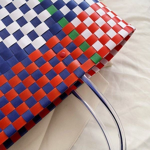 Macro shot of colorful checkered woven basket bag with clear handles and red button