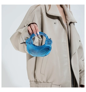 Close-up of bright blue acrylic handbag with spiral twisted handle and sculptural design