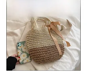 Detail of gradient straw woven handbag with dual handles and elegant satin ribbon bow