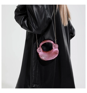Detail of pink metallic mini bag with pleated texture and golden chain on model