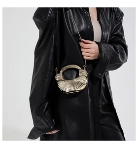 Detail view of a gold metallic evening bag with wave texture and chain strap