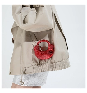 Detail of red acrylic crescent mini bag with spiral texture and metal chain strap