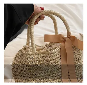 Detail of straw handbag with woven handle and elegant brown satin bow decoration
