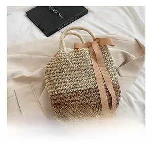 Detail of color-block straw handbag featuring a satin bow and woven dual straps