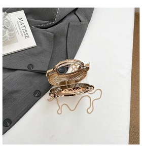 Detail of a golden shell-shaped clutch with metallic texture and sleek chain strap