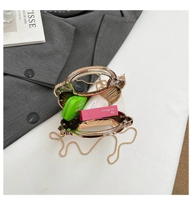 Detail of transparent acrylic mini evening bag with a textured gold metal handle and chain