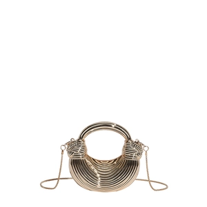 Detail of a crescent gold evening bag featuring horizontal textures and a round handle