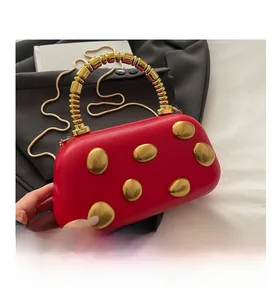 Detail showing red PU leather clutch bag with golden metal studs and segment handle