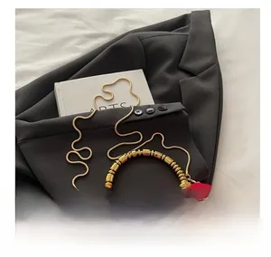 Macro detail of red PU leather box bag featuring golden studs and elegant bead handle