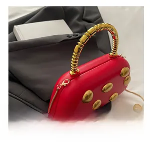 Detail of red PU leather box bag with gold metal handle and studded sphere ornaments