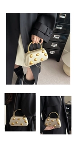 Detail of luxury gold hard shell clutch with 3D oval accents and pearl handle strap