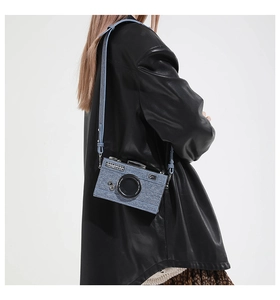 Détail du sac à bandoulière en forme d'appareil photo en denim bleu avec motif