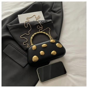 Detail of black evening box bag with pebble gold accents and snake chain strap