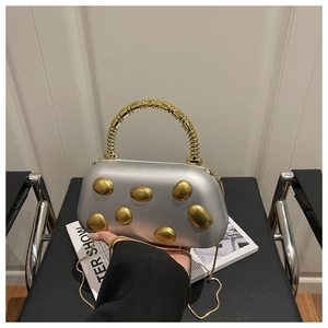 Close-up of a silver hard shell clutch bag with gold beads handle and chain strap