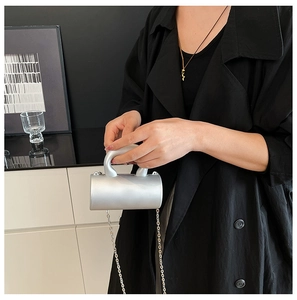 Gros plan d'un mini sac cylindrique argent mat avec poignée épaisse et chaîne fine