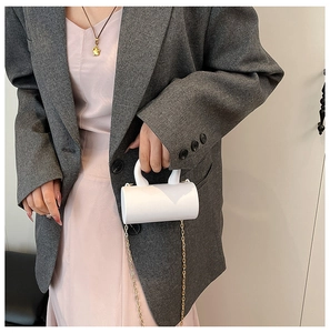 Gros plan du mini sac à main blanc cylindrique avec bandoulière en chaîne dorée
