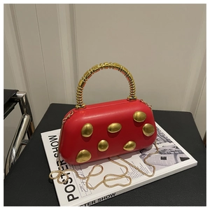 Detail of red PU box bag featuring gold pebble metal accents and a spiral top handle