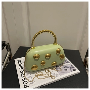 Detail of pistachio green PU box bag featuring gold metal studs and ring handle